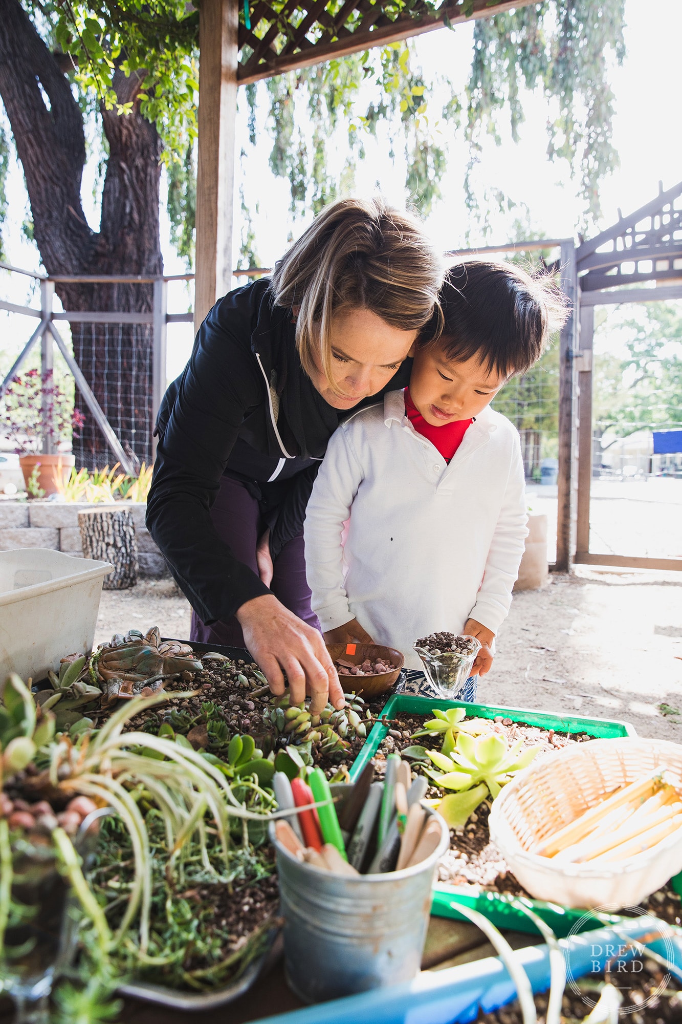 A teacher works with a young student in learning garden classroom at The Hillbrook School in Los Gatos, California. San Francisco education marketing photographer Drew Bird. San Jose school branding photographer.