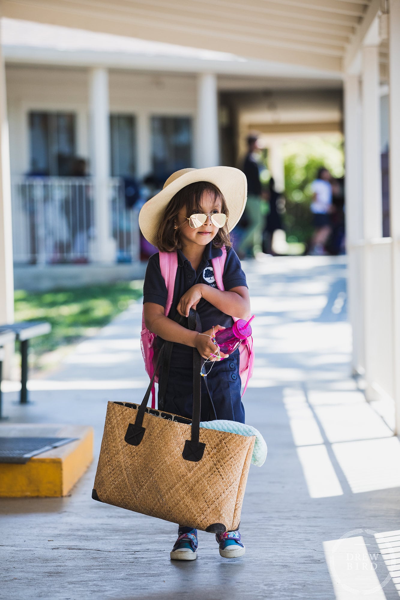 A girl wearing aviator sunglasses walks with a hand bag on campus at The Hillbrook School in Los Gatos, California. San Francisco education marketing photographer Drew Bird. San Jose school branding photographer.