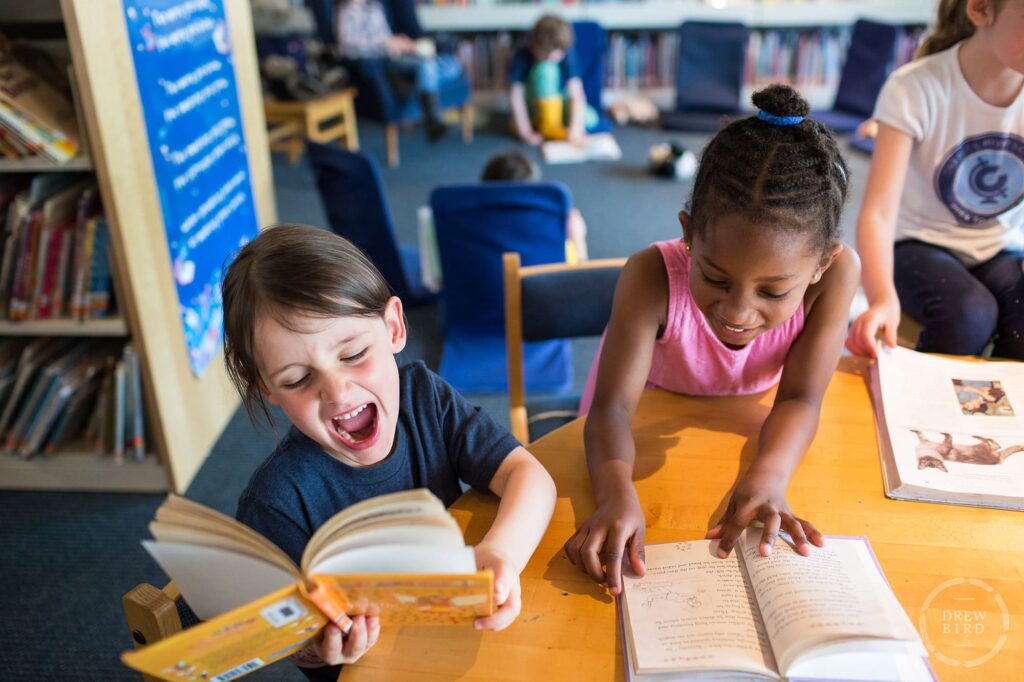 Two girls reading a book and laughing at the Charles River School in Boston. San Francisco education marketing photographer Drew Bird. San Jose school branding photographer.