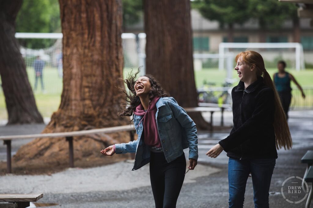 Two students laughing and walking together on campus at Alto International School in Menlo Park, California. San Francisco education marketing photographer Drew Bird. San Jose school branding photographer.