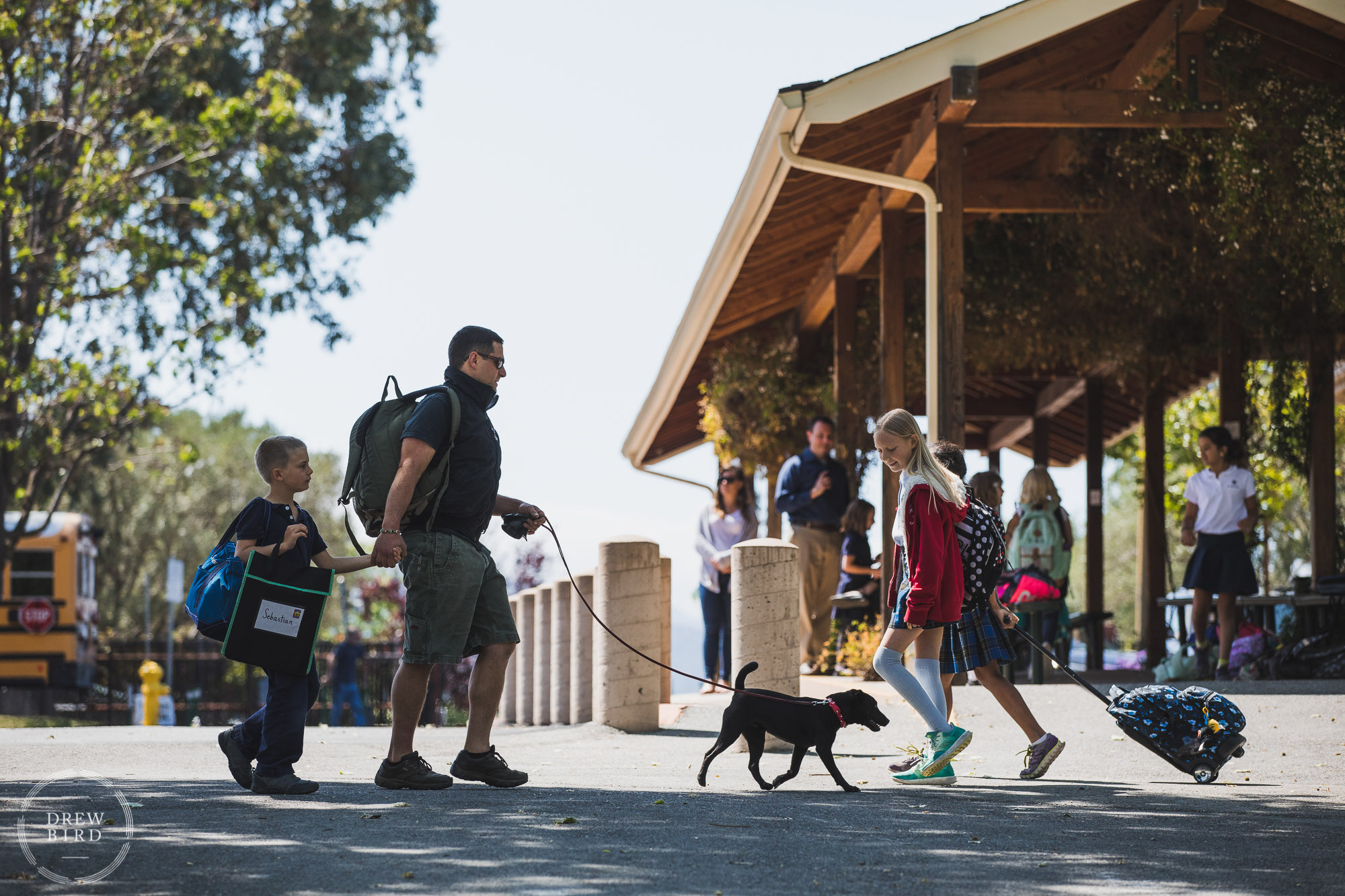 Students and parents arrive for the school day and walk across campus with their puppy dog on a leash. Hillbrook School. San Jose education brand photography and independent school photographer Drew Bird.